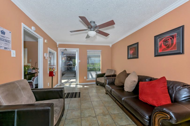a living room with brown leather couches and a ceiling fan at The Arlington Park Apartments