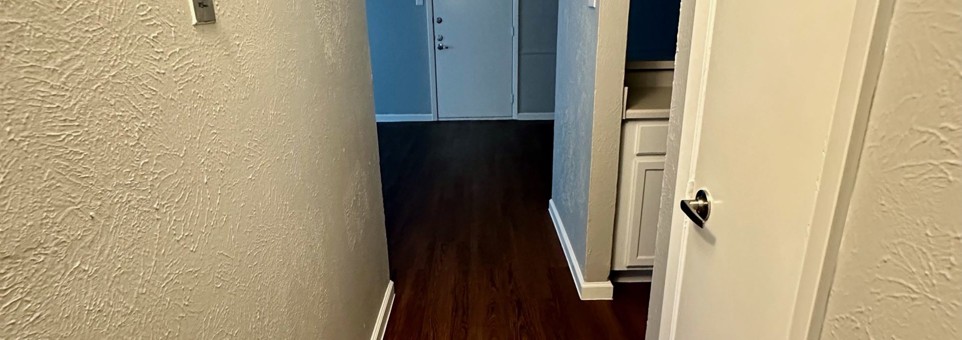 a hallway with hardwood floors and a door at The Arlington Park Apartments
