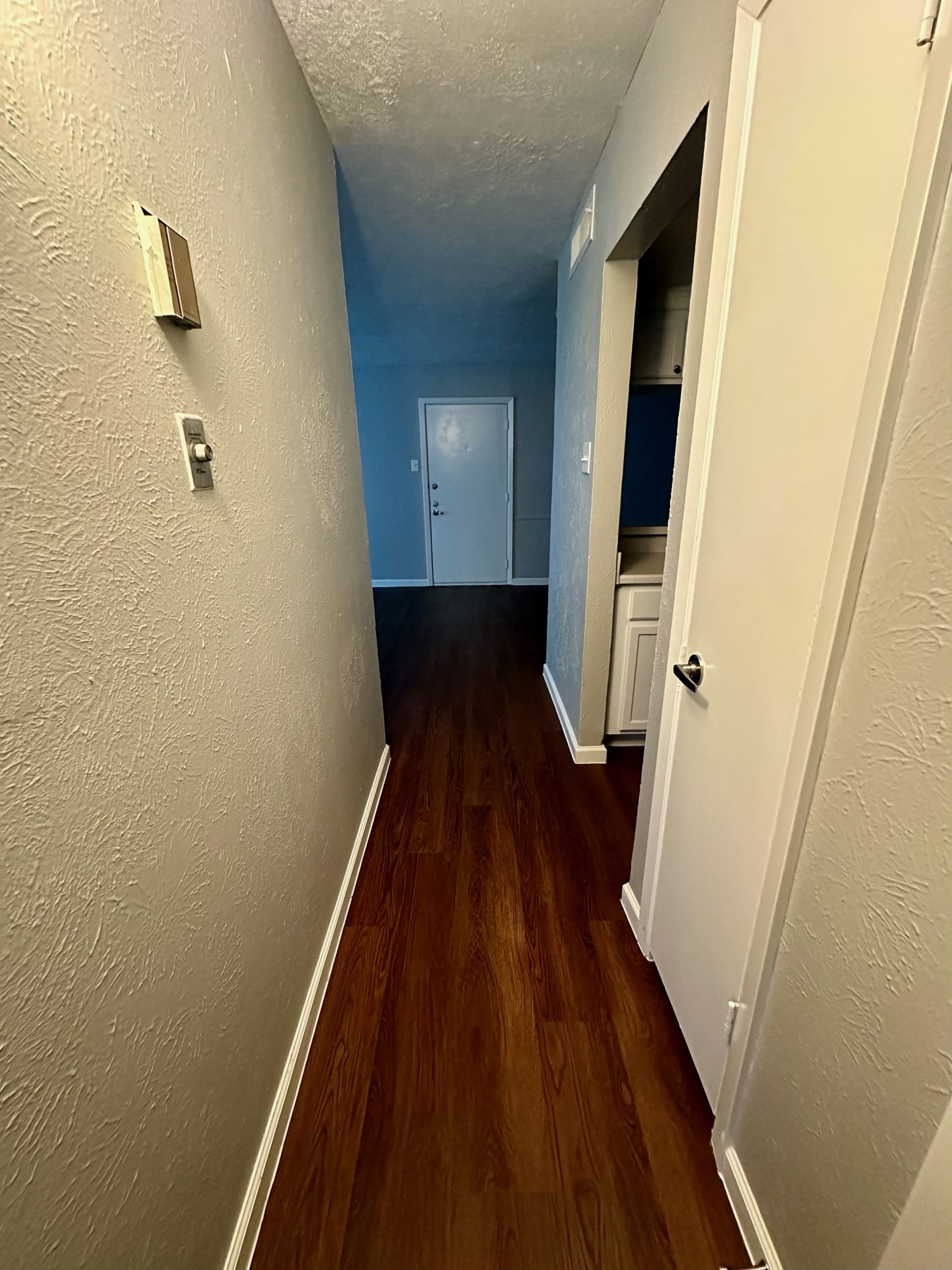 a hallway with hardwood floors and a door at The Arlington Park Apartments